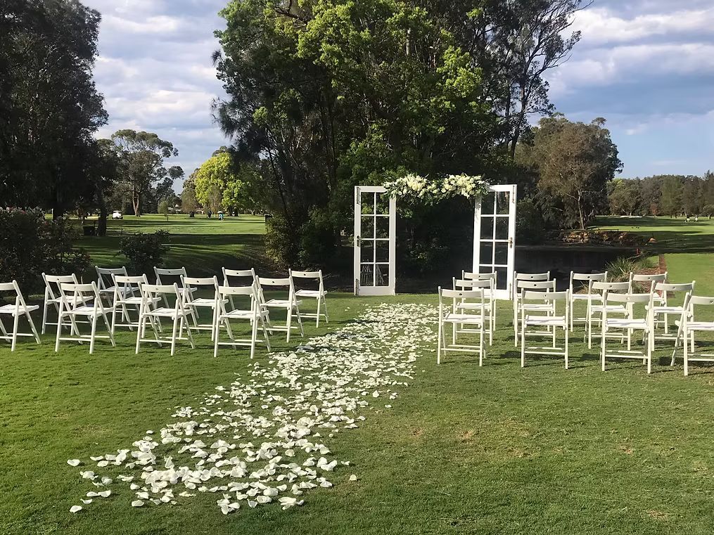 A Row of White Folding Chairs Are Lined Up in a Grassy Field ― Central Coast Events in Berkeley Vale, NSW