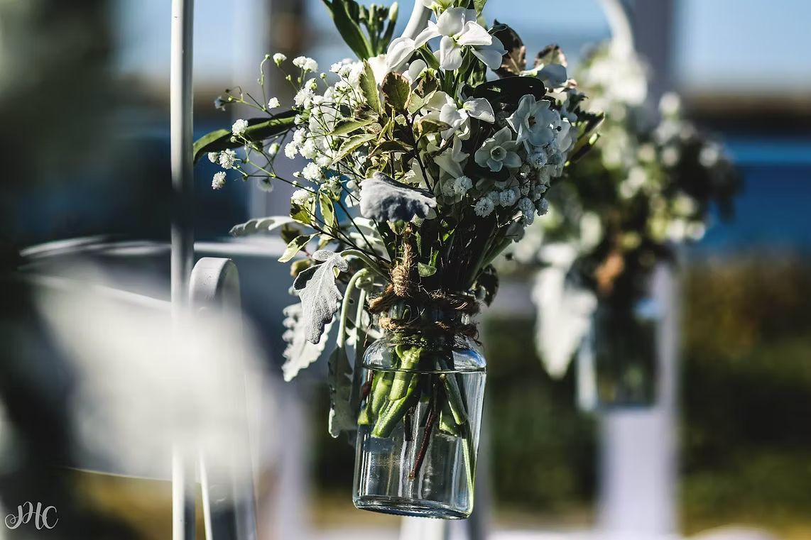 A Vase Filled With White Flowers is Hanging From a Pole ― Central Coast Events in Berkeley Vale, NSW