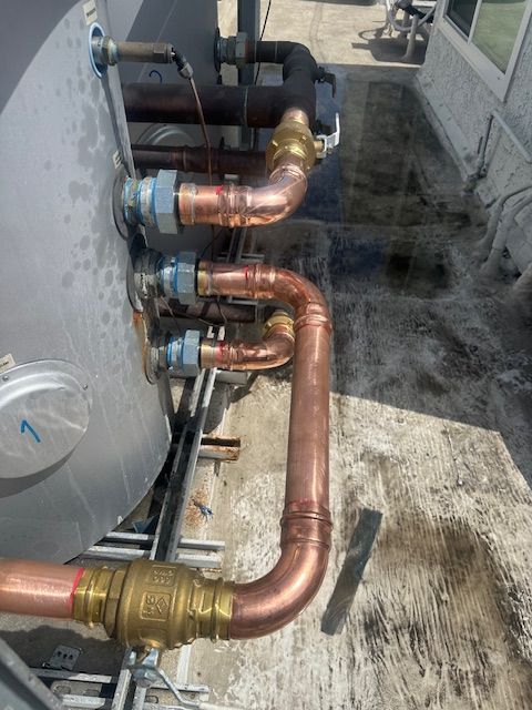 A bunch of copper pipes are connected to a metal tank.