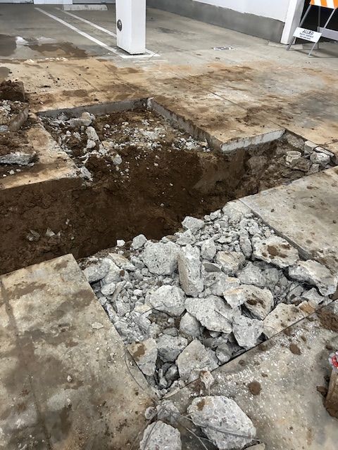 A pile of rocks is laying on the ground next to a hole in the ground.