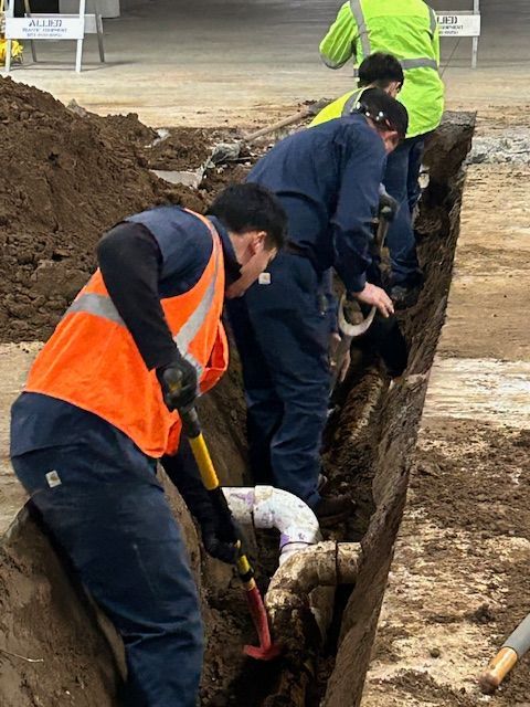 A group of construction workers are digging in a trench