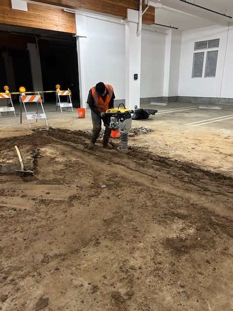 A man is working on a dirt floor in a garage.