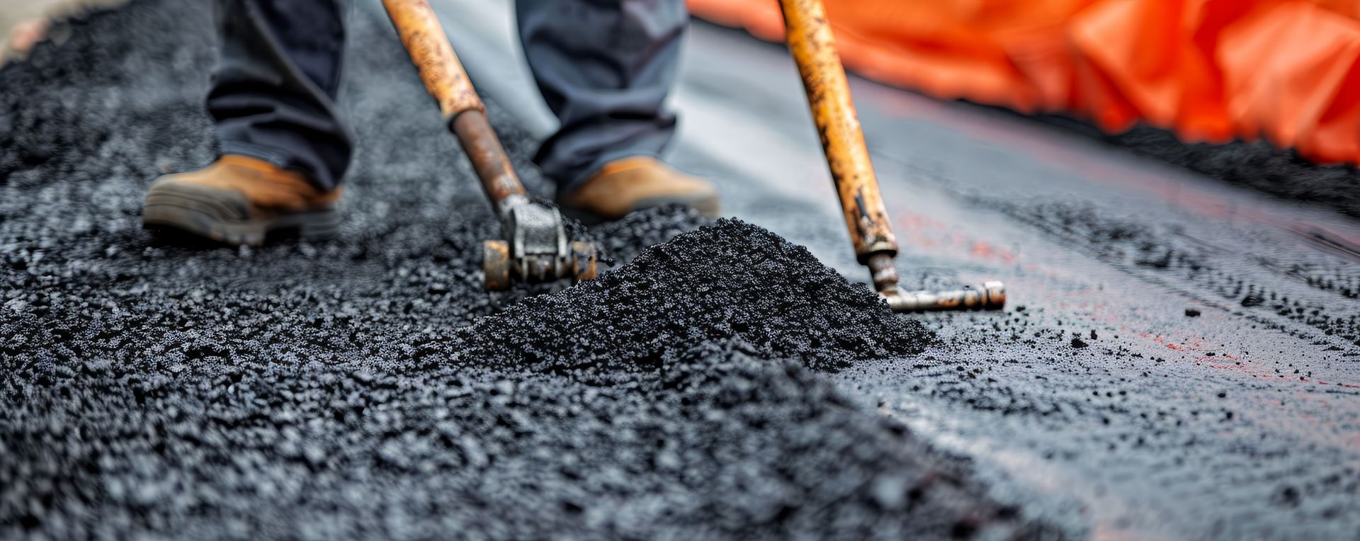 Workers using hand tools for professional asphalt repairing on a fresh blacktop surface project.