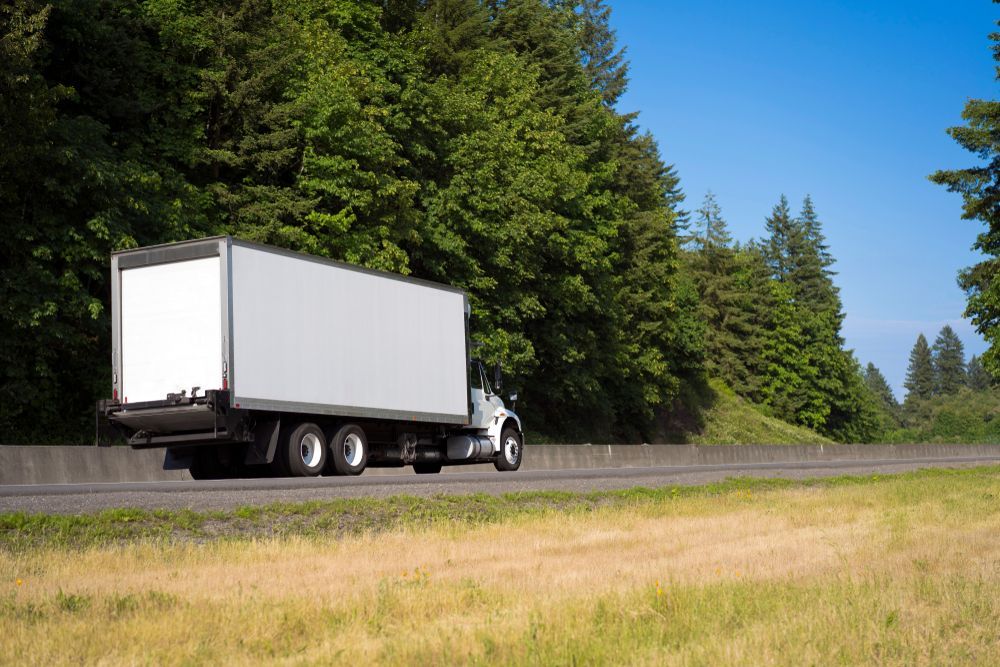 A White Semi-truck Driving Along a Highway Bordered — Far North Windscreens in Mareeba, QLD