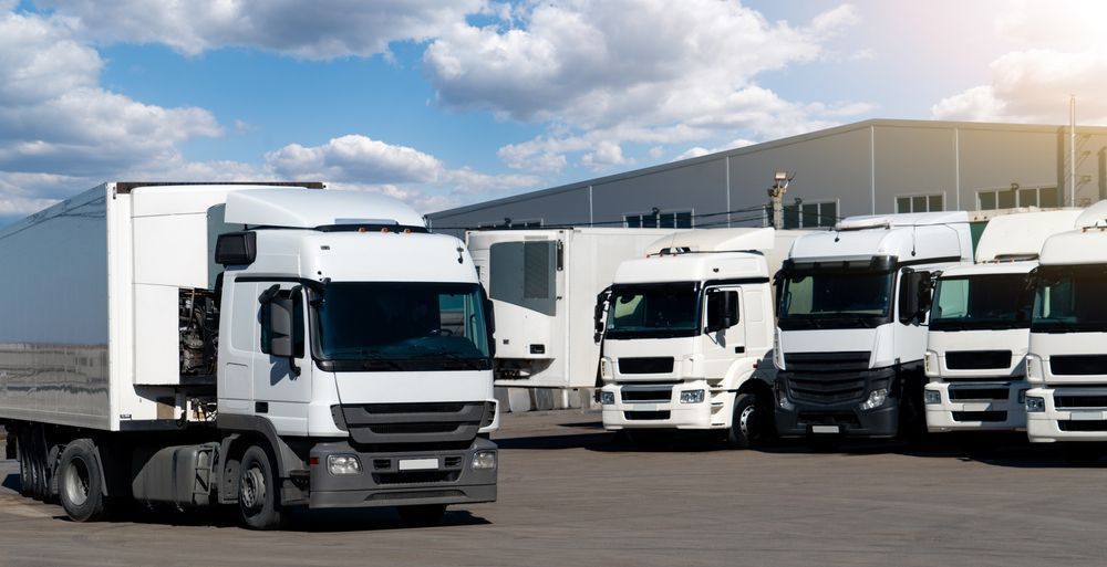 A Line of White Semi-trucks Parked in a Lot Outside a Large Warehouse — Far North Windscreens in Mareeba, QLD