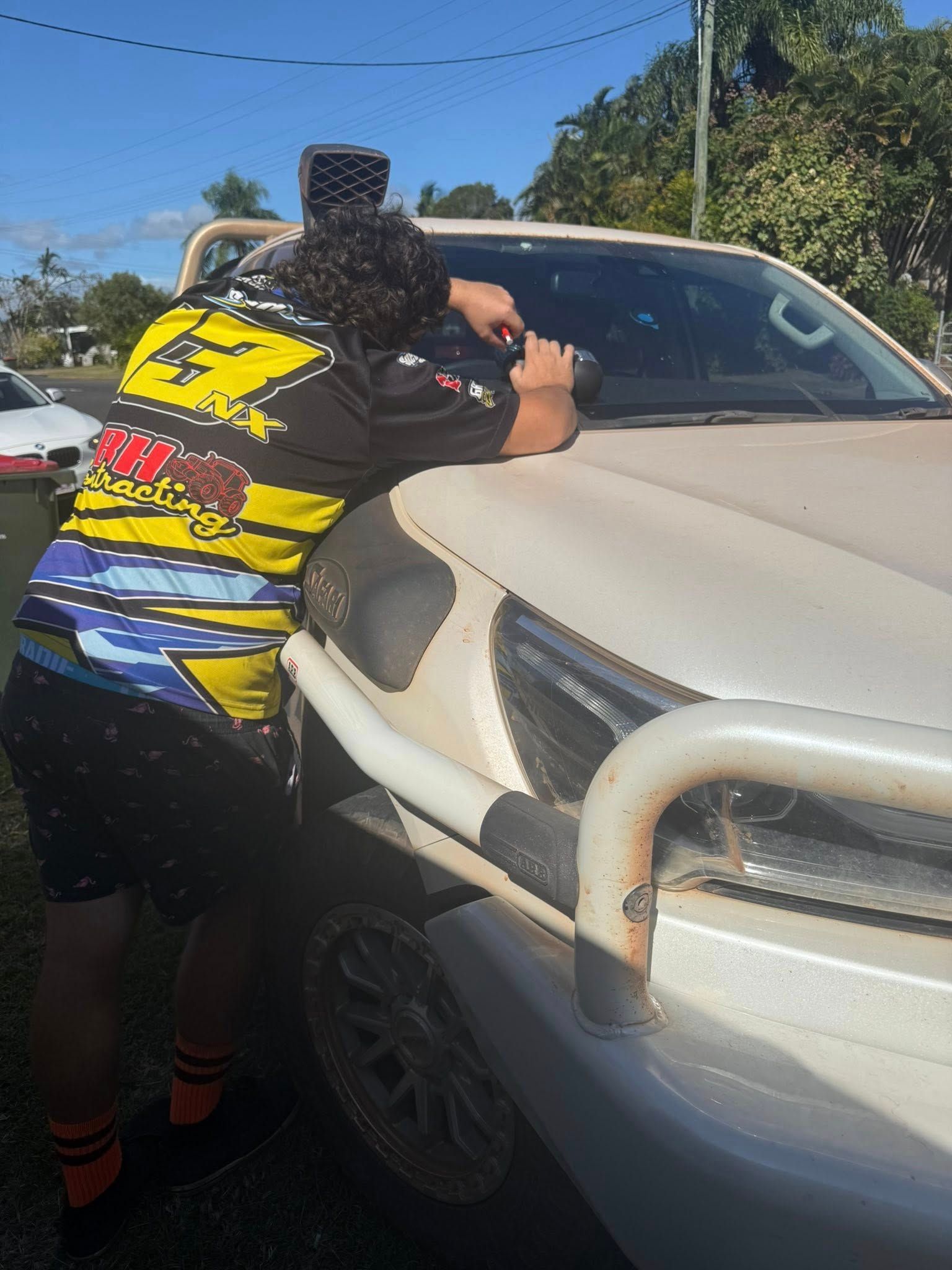 Person leaning on a white car hood, wearing a colourful shirt — Far North Windscreens in Mareeba, QLD