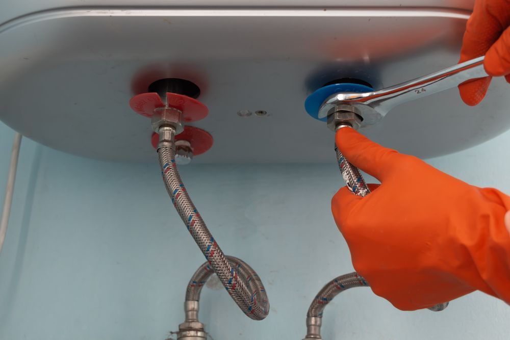 A person is fixing a water heater with a wrench.