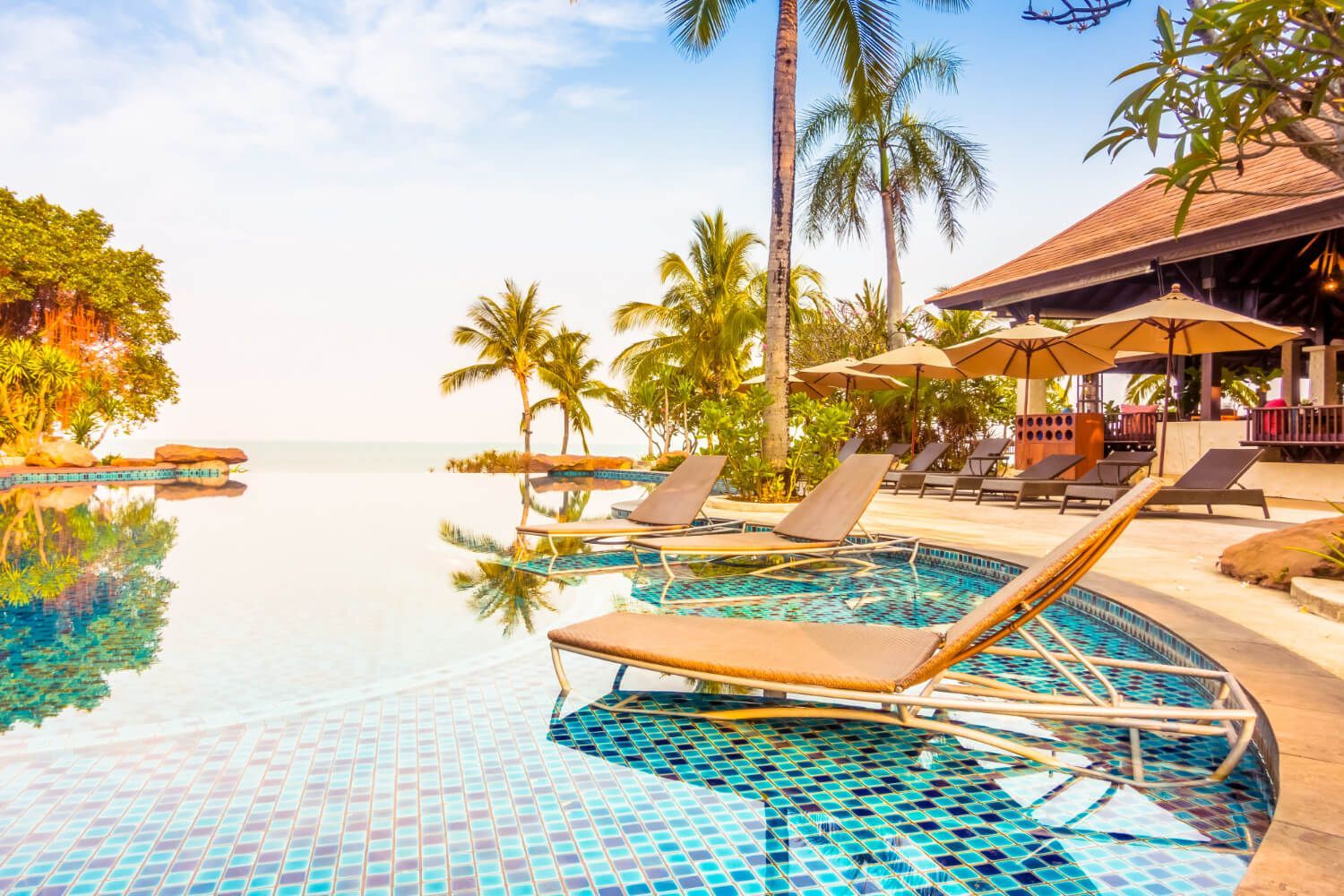 A swimming pool surrounded by lounge chairs and umbrellas at a resort.