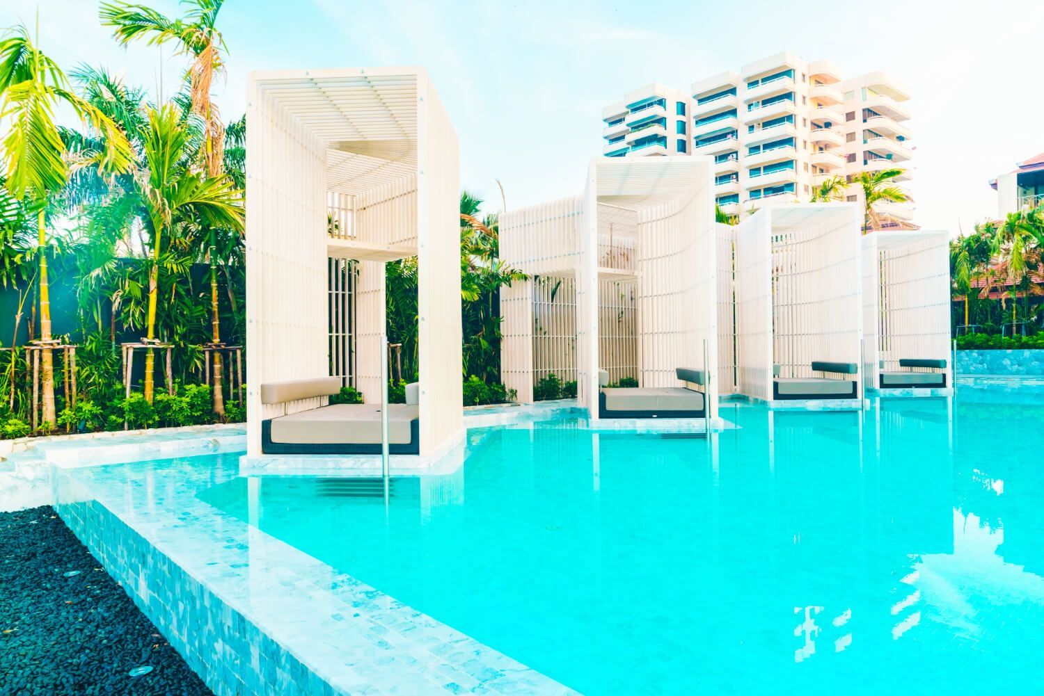 A large swimming pool surrounded by palm trees and buildings.