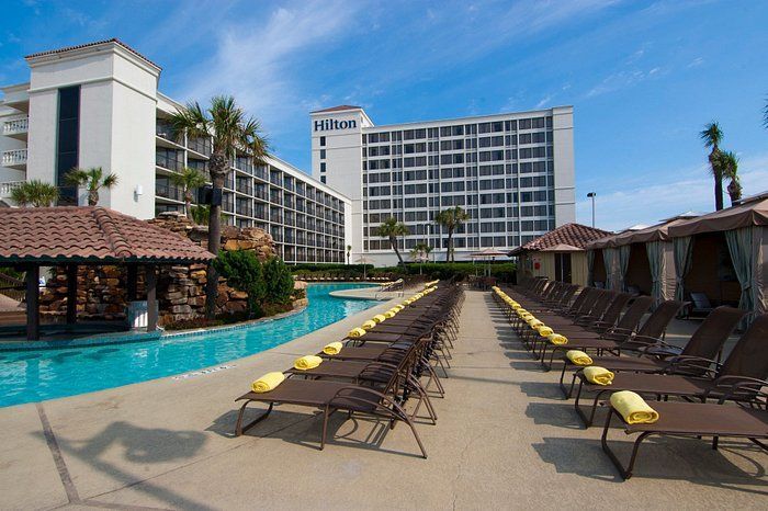 A large swimming pool surrounded by chairs and umbrellas in a resort.