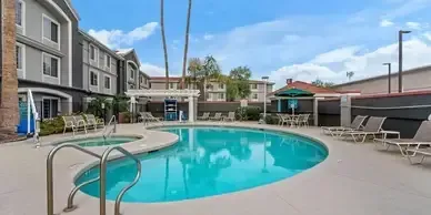 There is a large swimming pool in the middle of a hotel.
