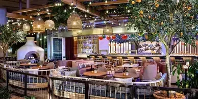 A restaurant with tables and chairs and a pizza oven.