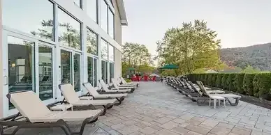 A row of lounge chairs are lined up on a patio in front of a building.