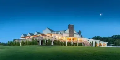 A large white house is sitting on top of a lush green hill.