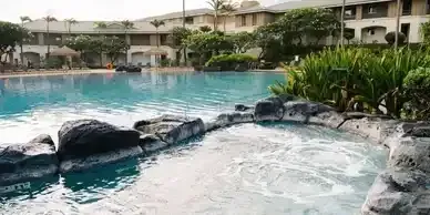A large swimming pool with a hot tub in the middle of it.