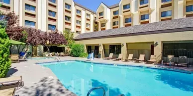 There is a large swimming pool in front of a hotel.