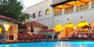 A large swimming pool with chairs and umbrellas in front of a building