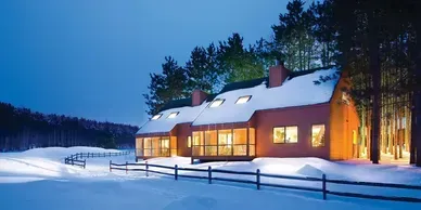 A house in the snow with a fence in front of it