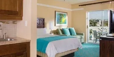 A hotel room with a king size bed , couch , sink and television.