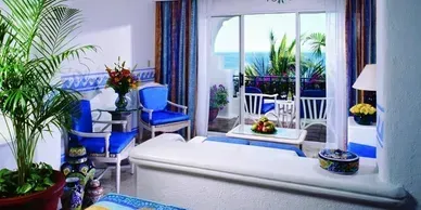 A living room with sliding glass doors leading to a balcony overlooking the ocean.
