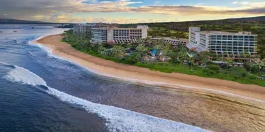 An aerial view of a beach with a hotel in the background.