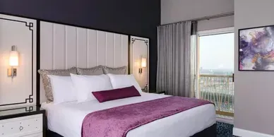A hotel room with a king size bed and a balcony.