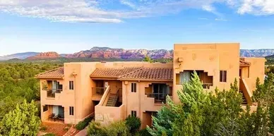 An aerial view of a large building surrounded by trees and mountains.