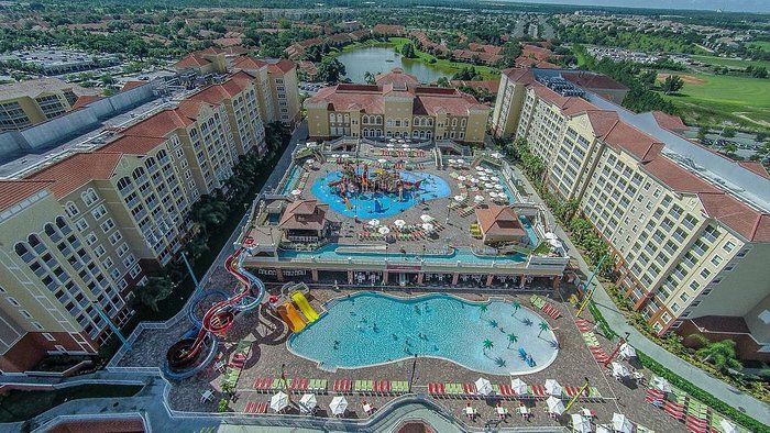 A large swimming pool surrounded by chairs and umbrellas in a resort.