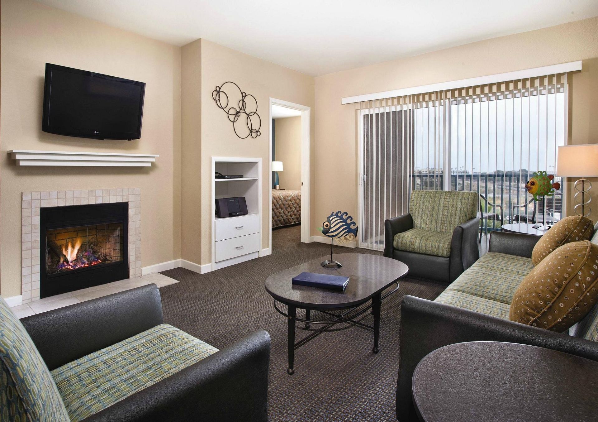 A living room with a couch , chairs , lamps and a balcony overlooking the ocean.