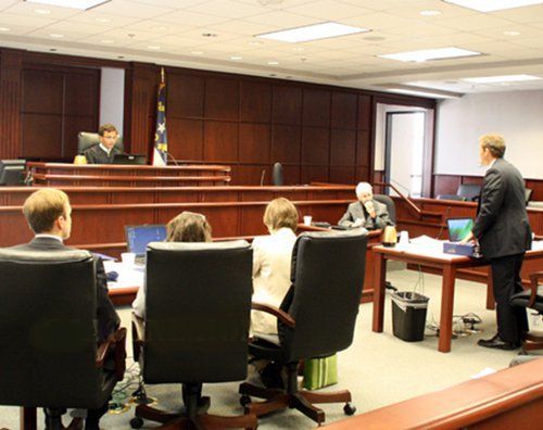 A group of people are sitting in chairs in front of a judge in a courtroom.