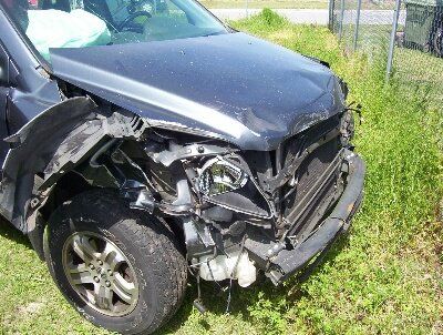 A damaged car is parked in a grassy field