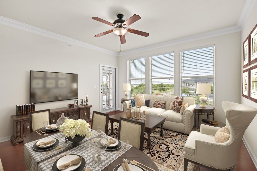 Senior apartment living room with a dining table, chairs, a ceiling fan, and a flat-screen tv at Marquis Rockwall in Rockwall, TX.