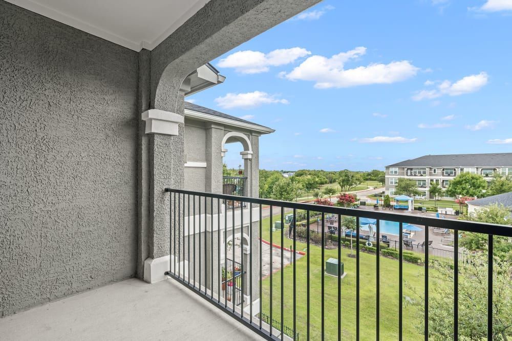 Spacious balcony with a view of a pool and a building at Marquis Rockwall in Rockwall, TX.