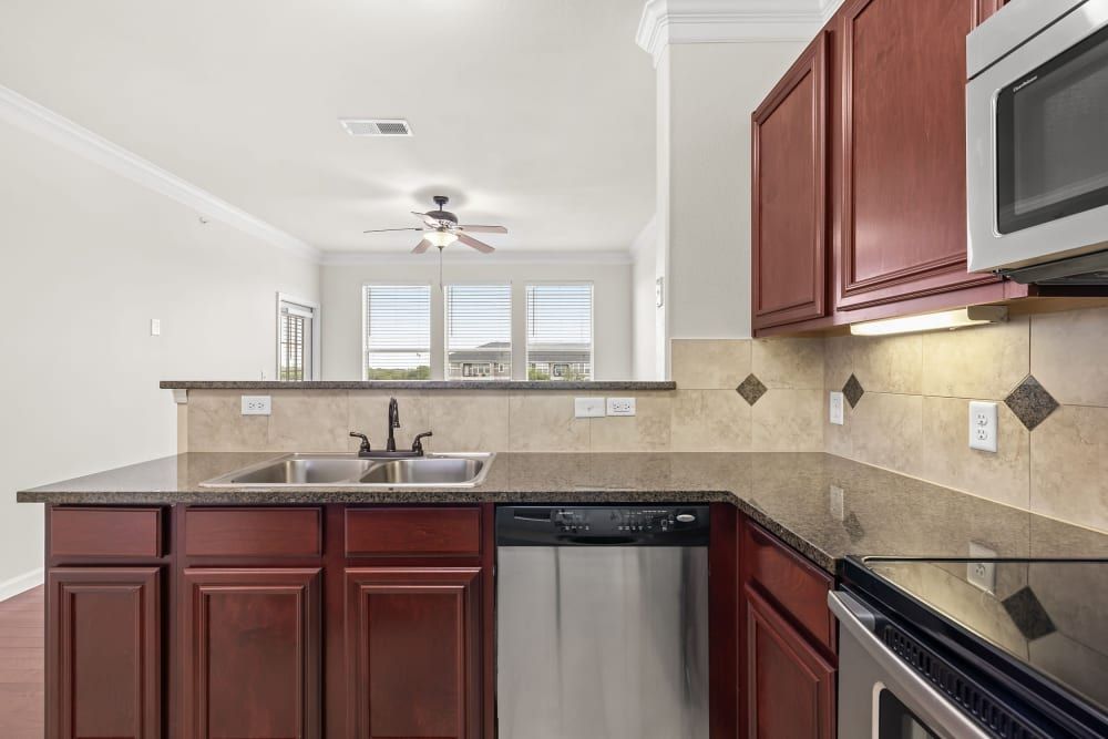 Senior apartment kitchen with stainless steel appliances and wooden cabinets at Marquis Rockwall in Rockwall, TX.