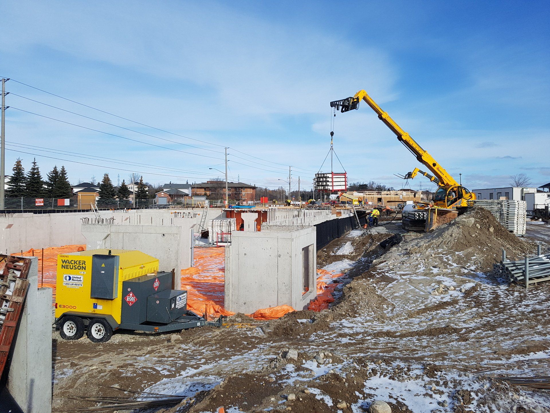 A construction site with a yellow crane and a compressor.