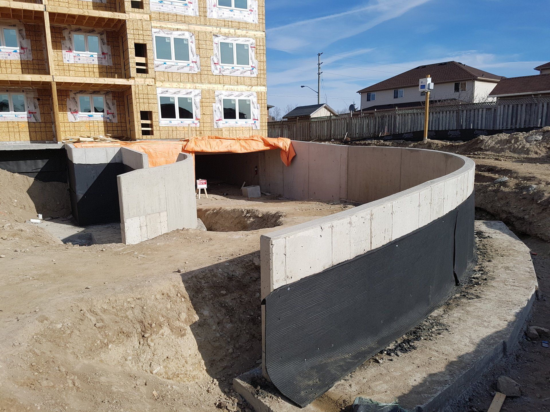 A large concrete wall is being built in front of a building under construction.