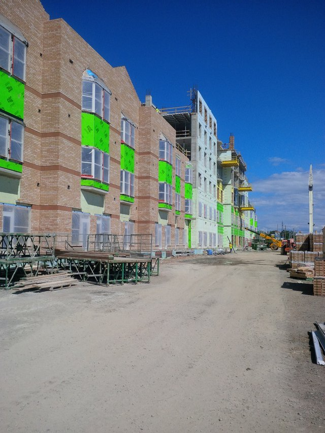 A large brick building with green windows is under construction