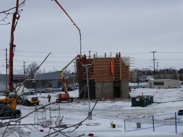 A concrete pump is being used to pour concrete into a building under construction
