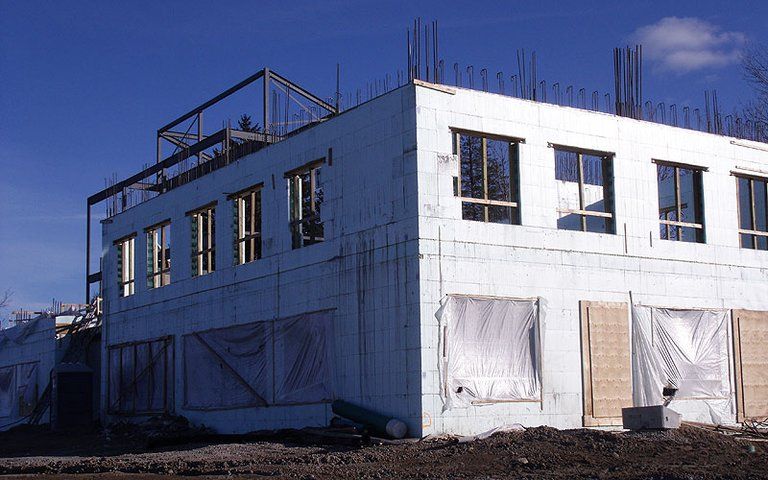 A large white building under construction with a blue sky in the background.
