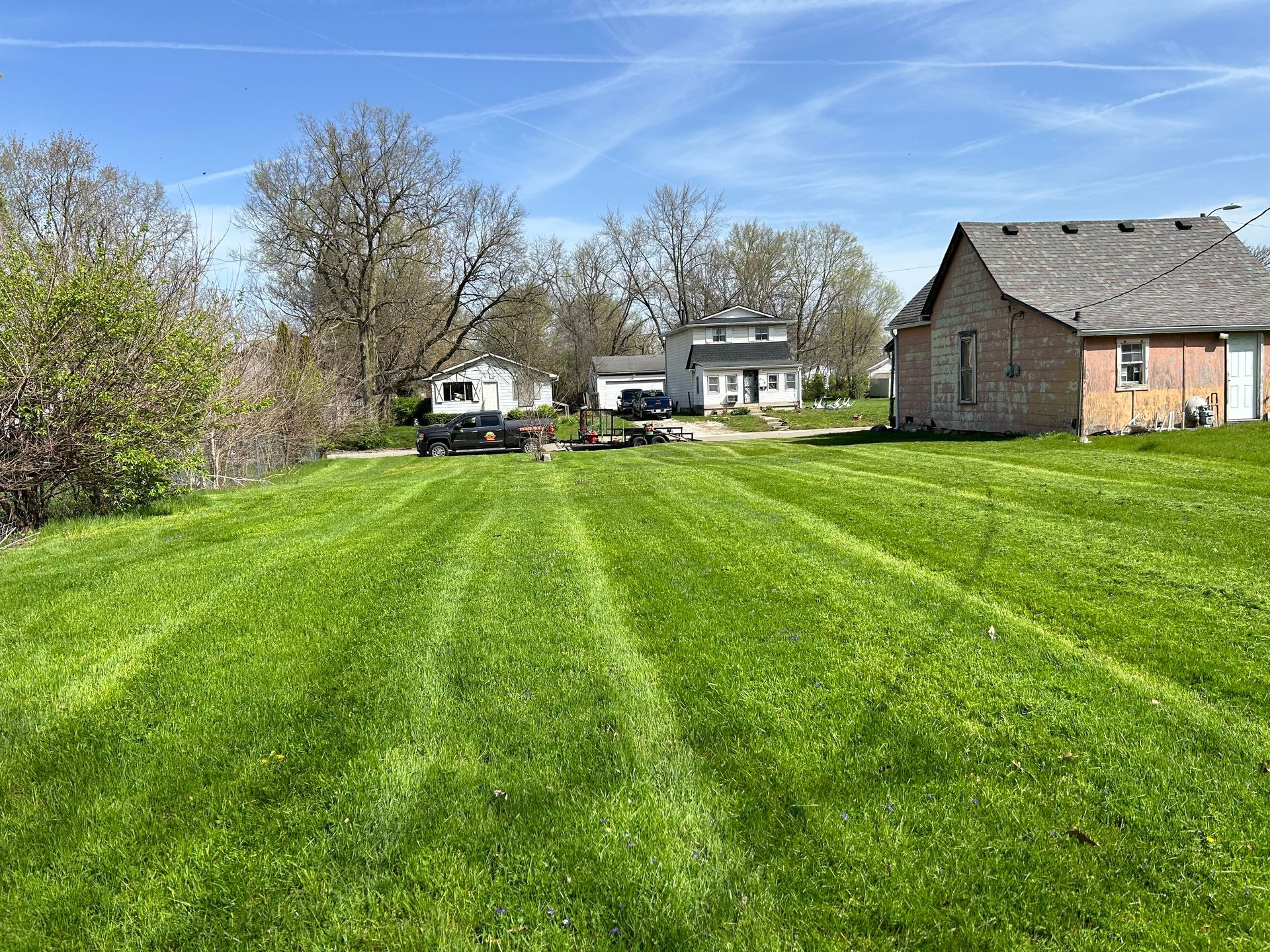 A lush green lawn with a fence and bushes surrounding it.