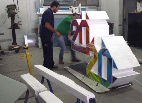 Due operai trasportano una colorata struttura geometrica di una casa in un'officina.