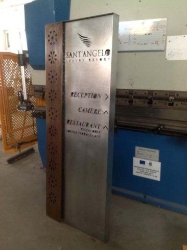 Un cartello alto in metallo per il Sant'Angelo Natural Resort. Mostra le indicazioni per raggiungere la reception, le camere e il ristorante.
