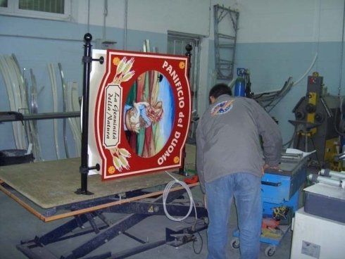 Uomo al lavoro su un'insegna per