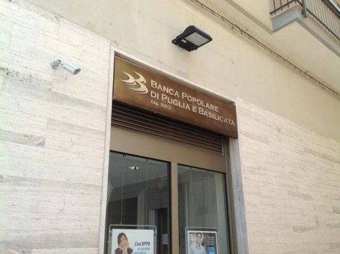 Entrance to Banca Popolare di Puglia e Basilicata bank. Sign above doorway; security camera to the left.