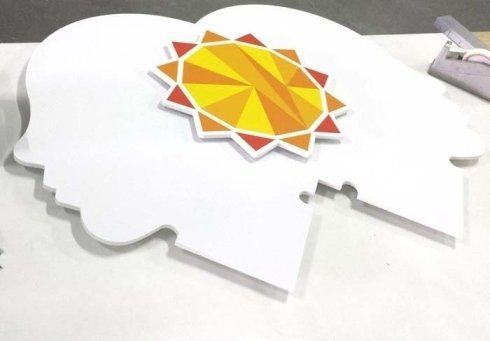 Sagoma in schiuma bianca a forma di testa umana, con al centro un motivo a raggiera giallo e arancione.