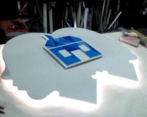 Insegna luminosa bianca con il logo della casa blu in alto.