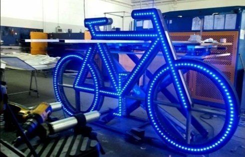 Grande display per biciclette illuminato a LED blu. All'interno dell'officina. Ruota anteriore su rulli.