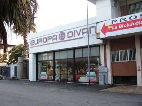 Esterno di un negozio di mobili chiamato Europa Divani con un'insegna rossa che indica un negozio di biciclette.