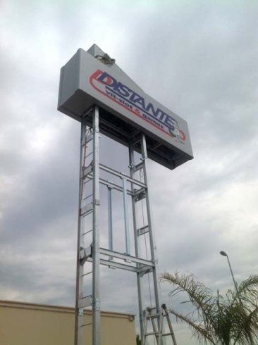 Cartello per Distante Distributors su un pilone metallico contro un cielo nuvoloso.