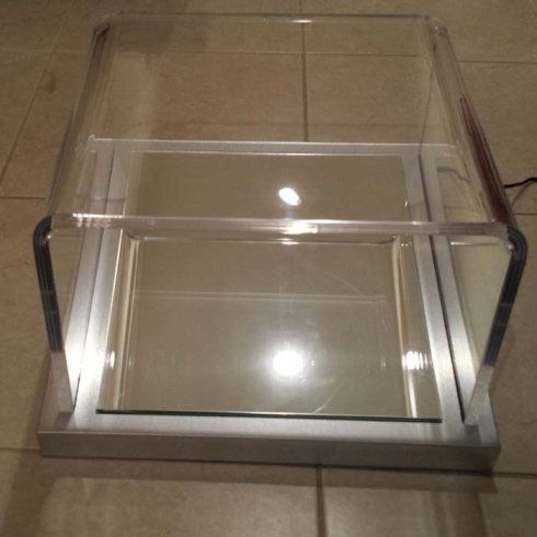 Vetrina in acrilico trasparente con interno a specchio e finiture in metallo.